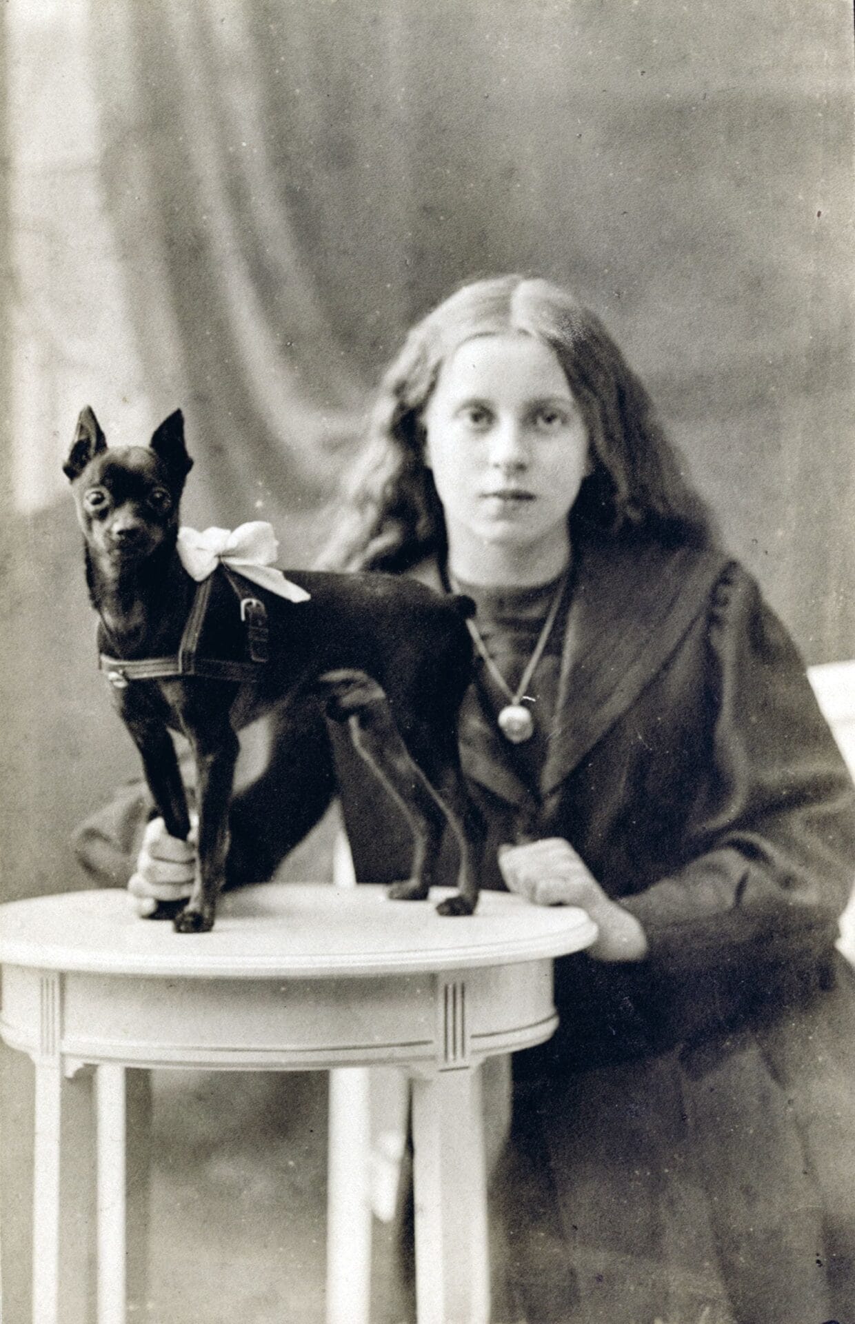 Fotografía en blanco y negro de una mujer junto a un perro pequeño